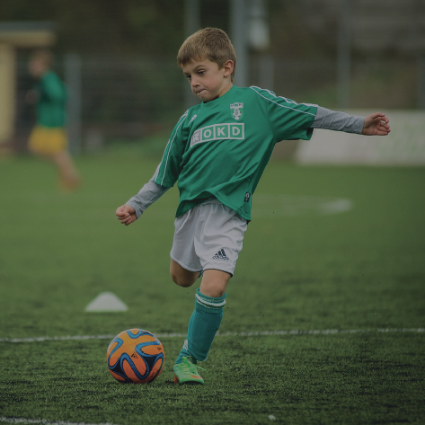 Picture of young boy kicking a soccer ball.